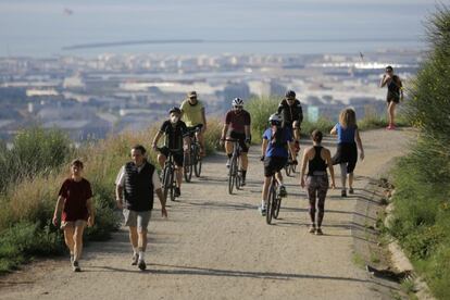 Ciclistas y corredores practican deporte por la carretera de Les Aigües, en Barcelona.