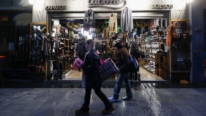 Madrileños y turistas pasan delante de una tienda del centro de Madrid.