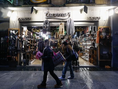 Madrileños y turistas pasan delante de una tienda del centro de Madrid.