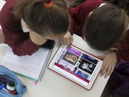 Dos niñas trabajan en clase con una tableta.