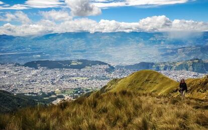 Una senderista subiendo al Pichincha (4.784 metros), uno de los volcanes andinos que rodean la ciudad de Quito, al fondo.