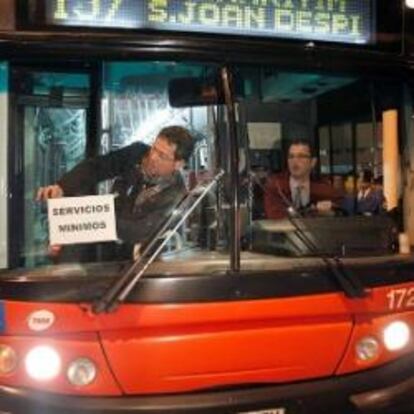 Un empleado de Transportes Metropolitanos de Barcelona coloca un cartel en uno de los autobuses que esta madrugada salieron para cumplir con los servicios mínimos de transporte pactados el día de la huelga general, 29 de marzo de 2012