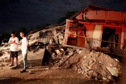 Unos j&oacute;venes permanecen junto a unos escombros durante el velorio de un allegado en Manta (Ecuador).