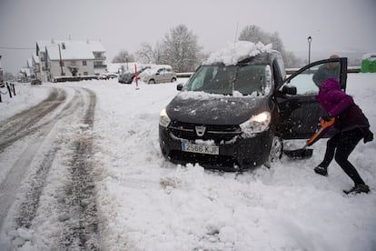 Una mujer limpia la nieve de su vehículo en Burguete, Navarra, el lunes.
