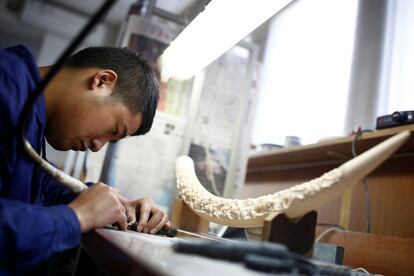 Un hombre trabaja sobre una pieza de marfil en un taller en Pekín (China).