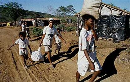 Unas mujeres regresan a su campamento en el Estado de Pernambuco con sacos de comida de una donación.