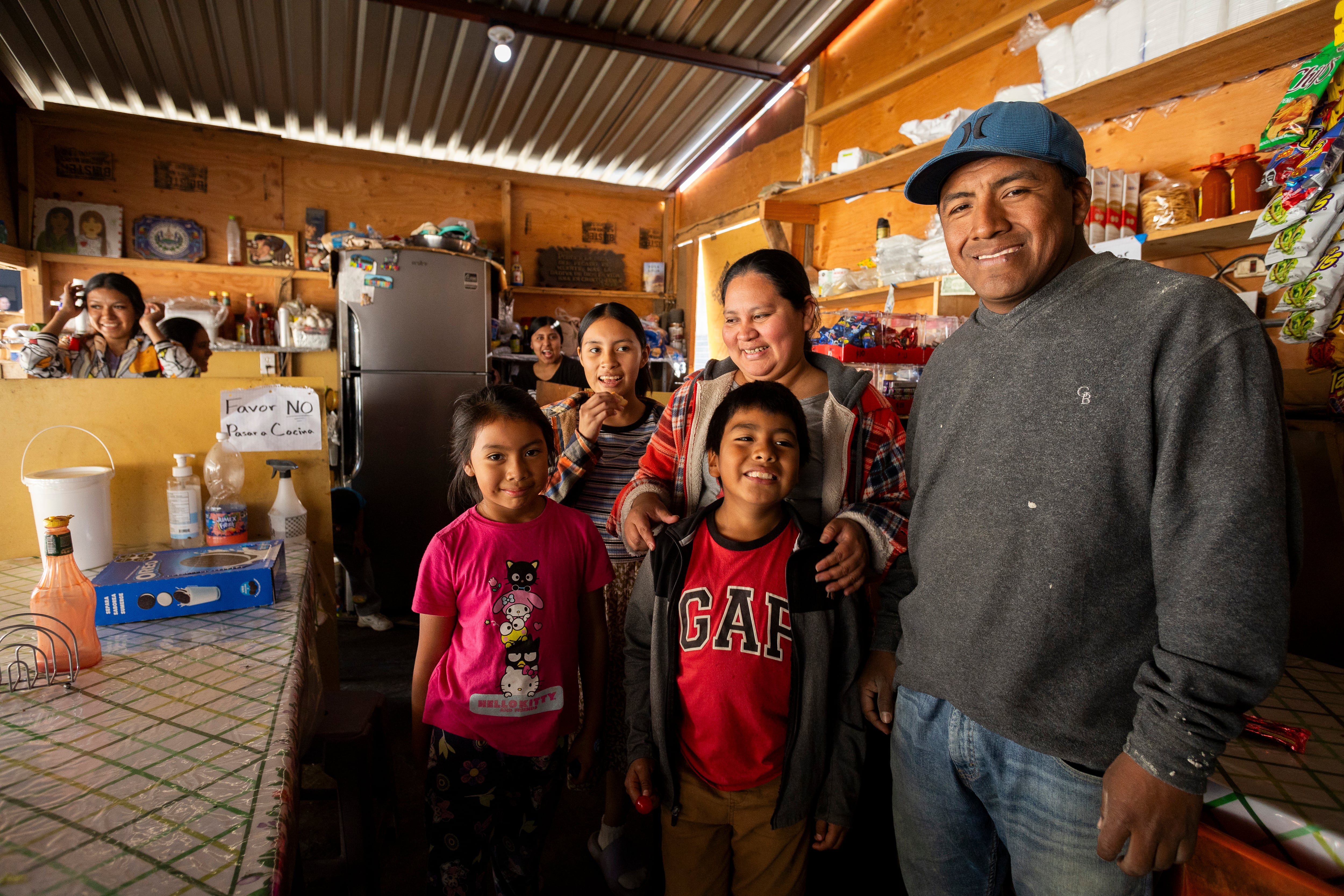 Rocío, Stephany y Benjamín Miranda, posan con sus padres Rocío Janet Ramos y Josué Miranda en el puesto de comida que han instalado en el Albergue Embajadores de Jesús, en Tijuana.