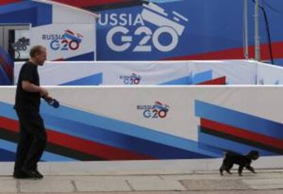 Un hombre pasea con su perro junto a carteles que anuncian la próxima cumbre del G20 que se celebrará en la ciudad rusa de San Petesburgo los días 5 y 6 de septiembre, en San Petesburgo (Rusia).