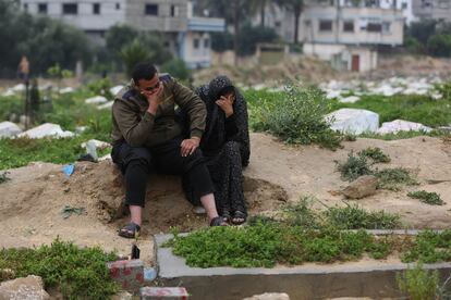 Familiares de palestinos fallecidos lloran ante sus tumbas en un cementerio, tras el primer día de Eid al-Fitr, este miércoles en el centro de la franja de Gaza.