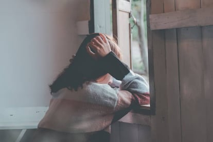 Una joven mira por la ventana.