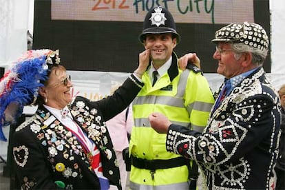 Una pareja vestida con prendas tradicionales británicas contagia su alegria a un policía en Trafalgar Square, después de hacerse pública la designación de la capital británica como sede de los Juegos Olímpicos de 2012.