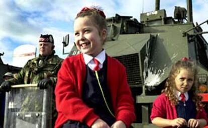 Un grupo de colegialas, ayer, mirando a lo lejos desde una calle cortada en la zona de Belfast (Irlanda del Norte).