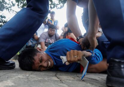 Policías filipinos inmovilizan a un manifestante durante una protesta contra la minería celebrada a pocos metros del lugar donde tenía lugar una conferencia sobre minería, en Pasay City, al suroeste de Manila (Filipinas).