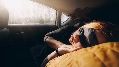 Una mujer durmiendo en el colchón hinchable en el coche.