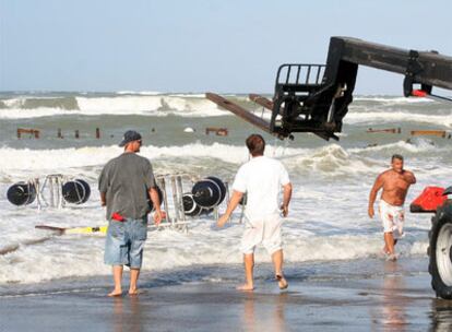 Operarios retiran objetos del agua donde se debían disputar las pruebas en Ostia