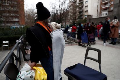 Varias personas esperan su turno para recibir alimentos, este jueves, en la plaza de San Amaro en Madrid.