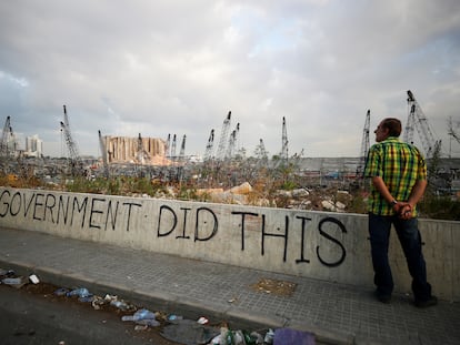 FILE PHOTO: A man stands next to graffiti at the damaged port area in the aftermath of a massive explosion in Beirut, Lebanon August 11, 2020. REUTERS/Hannah McKay     TPX IMAGES OF THE DAY/File Photo