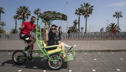 Un ‘bicitaxista‘ amb una parella de turistes al passeig de Colom de Barcelona.