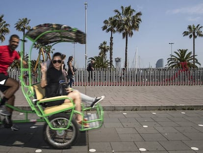 Un ‘bicitaxista‘ amb una parella de turistes al passeig de Colom de Barcelona.