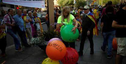 Una mujer escribe consignas a favor del referéndum del 1 de octubre en Cataluña en globos de colores en una concentración en Barcelona.