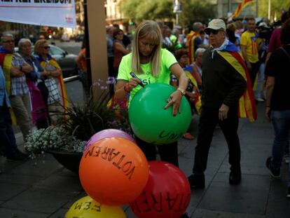 Una mujer escribe consignas a favor del referéndum del 1 de octubre en Cataluña en globos de colores en una concentración en Barcelona.