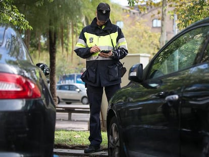 Un agent de la Guàrdia Urbana multa un vehícle estacionat en zona blava a Barcelona.