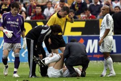 Casillas, el árbitro y Roberto Carlos observan a un jugador del Madrid que es atendido por los servicios médicos de su equipo.