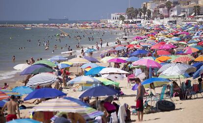 Playa de Regla, en Chipiona (C&aacute;diz), atestada de ba&ntilde;istas y sombrillas.