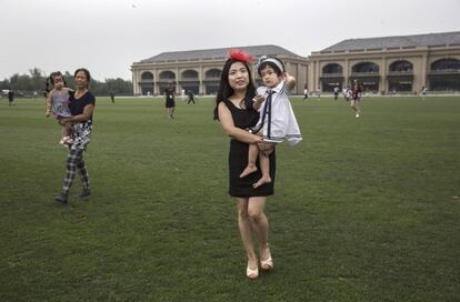 Una mujer china camina por el campo, con su hija en brazos, durante un intermedio del partido. Muchos de los clubes de polo en China están ligados a inmobiliarias de lujo.