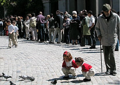 Dos niñas juegan con las palomas delante de la fila de ciudadanos que se formó auer a las puertas del Museo del Prado.
