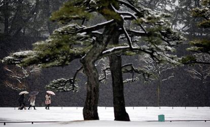 Visitantes recorren los parques del Palacio Imperial en Tokyo, cubiertos por la nieve.