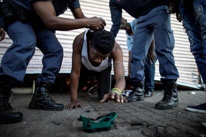 Un presunto saqueador es detenido en Soweto (Johannesburgo) por agentes de policía sudafricanos cuando sale de una tienda de propiedad extranjera.