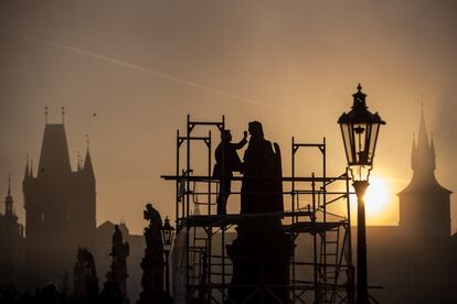 Un hombre restaura una de las estatuas del puente de Carlos en Praga (República Checa), el 25 de octubre.