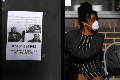 El cartel de una de las desaparecidas en el incendio colocado en el metro de Londres. Detrás, una mujer con mascarilla observa el lugar cercano al incendio, el 15 de junio.