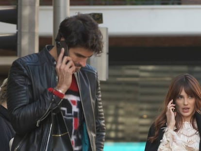 Los actores Andrea Duro y Juan Betancourt hablan por el móvil mientras caminan.