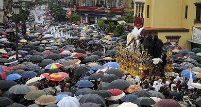 Miles de personas contemplan cómo miembros de la Hermandad de San Gonzalo protegen las imágenes, en Sevilla.