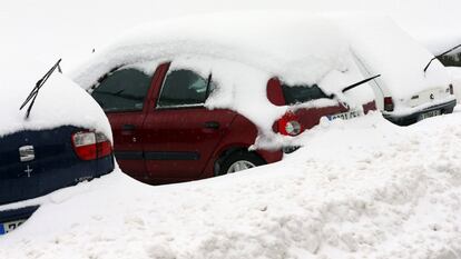 Varios vehículos permanecen cubiertos de nieve en la carretera del puerto de Pajares (Asturias).