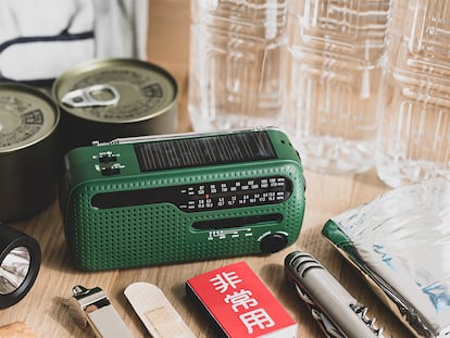 Una radio analógica en la mesa junto a más objetos útiles en el kit de emergencia.