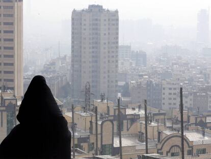 Una mujer observa la neblina y el humo entre los edificios en Teher&aacute;n (Ir&aacute;n) 