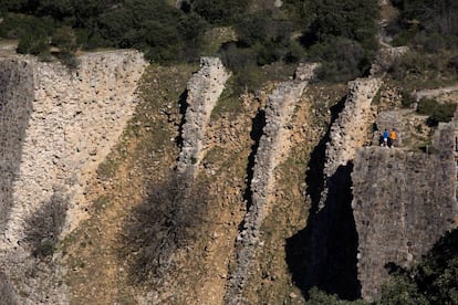 Dos jóvenes caminan sobre la presa del Gasco, en el cauce del río Guadarrama.