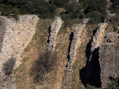 Dos jóvenes caminan sobre la presa del Gasco, en el cauce del río Guadarrama.