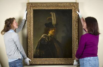 Dos trabajadoras del National Trust sostienen el autorretrato de Rembrandt.