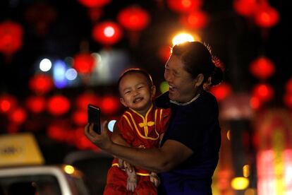 Una mujer se toma un selfi con un niño disfrazado en una calle decorada con lámparas chinas durante la celebración del Año Nuevo Lunar chino en Yangon (Myanmar), el 25 de enero de 2017.