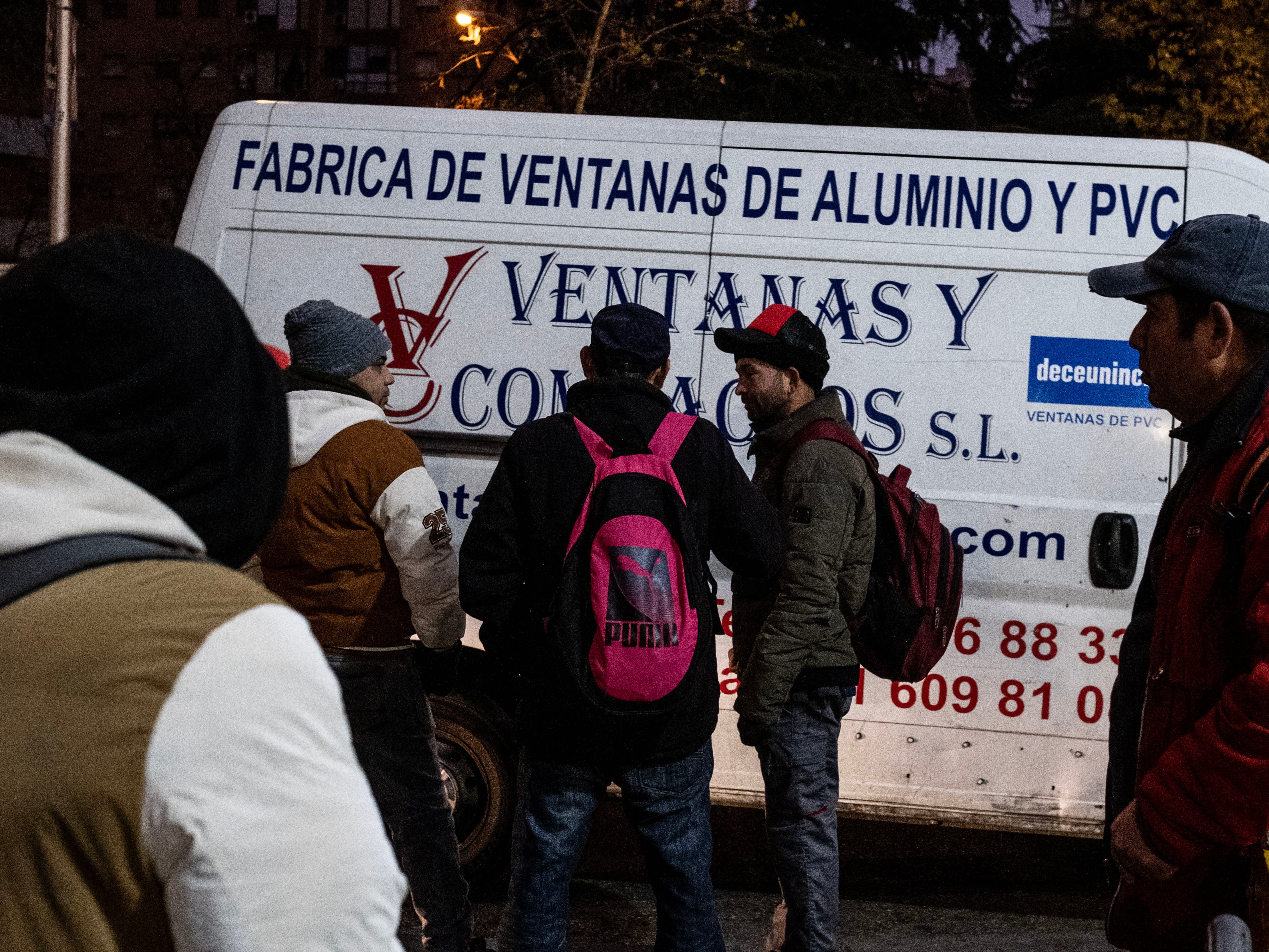 Jorge Luis, de espaldas a la izquierda, espera en Usera cada mañana a que le ofrezcan trabajo como albañil.