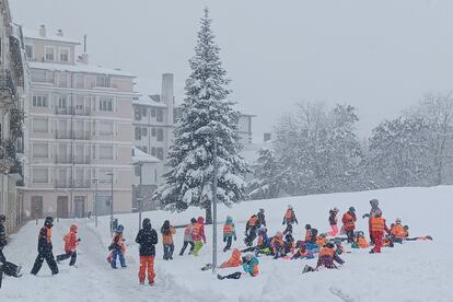 Varios escolares juegan con la nieve que a empezado a caer la madrugada del lunes en la localidad oscense de Jaca, en el Pirineo aragonés.