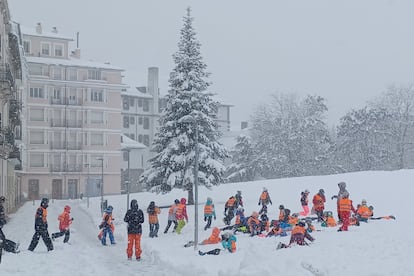 Varios escolares juegan con la nieve que a empezado a caer la madrugada del lunes en la localidad oscense de Jaca, en el Pirineo aragonés.