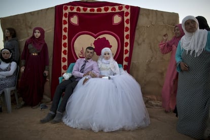 El refugiado sirio Ahmad Khalid, de 21 años, y su novia Fatheya Mohammed también de 21 años, se sientan frente a la tienda de su familia durante la ceremonia de boda en un asentamiento de tiendas de campaña informal cerca de la frontera con Siria, en las afueras de Mafraq, Jordania.