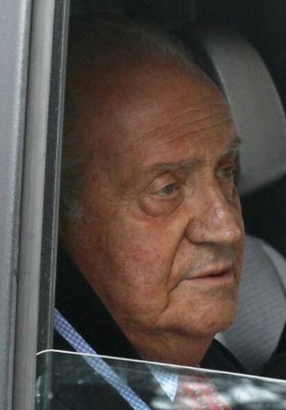 Spain's King Juan Carlos looks on from inside a car as he leaves a Madrid hospital after being discharged.