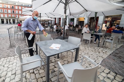 A waiter disinfects a table at a sidewalk café in Madrid.