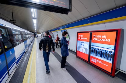 Varias personas frente a un cartel digital contra el presidente del Gobierno, en el metro de la Puerta del Sol, el 19 de mayo, en Madrid.